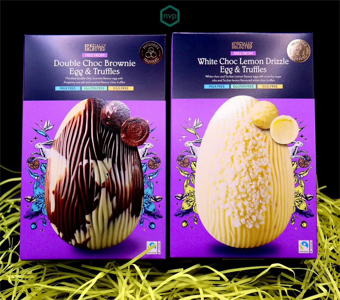 Two Specially Selected Easter egg cartons in purple, printed with the decorated eggs inside and set in yellow paper grass