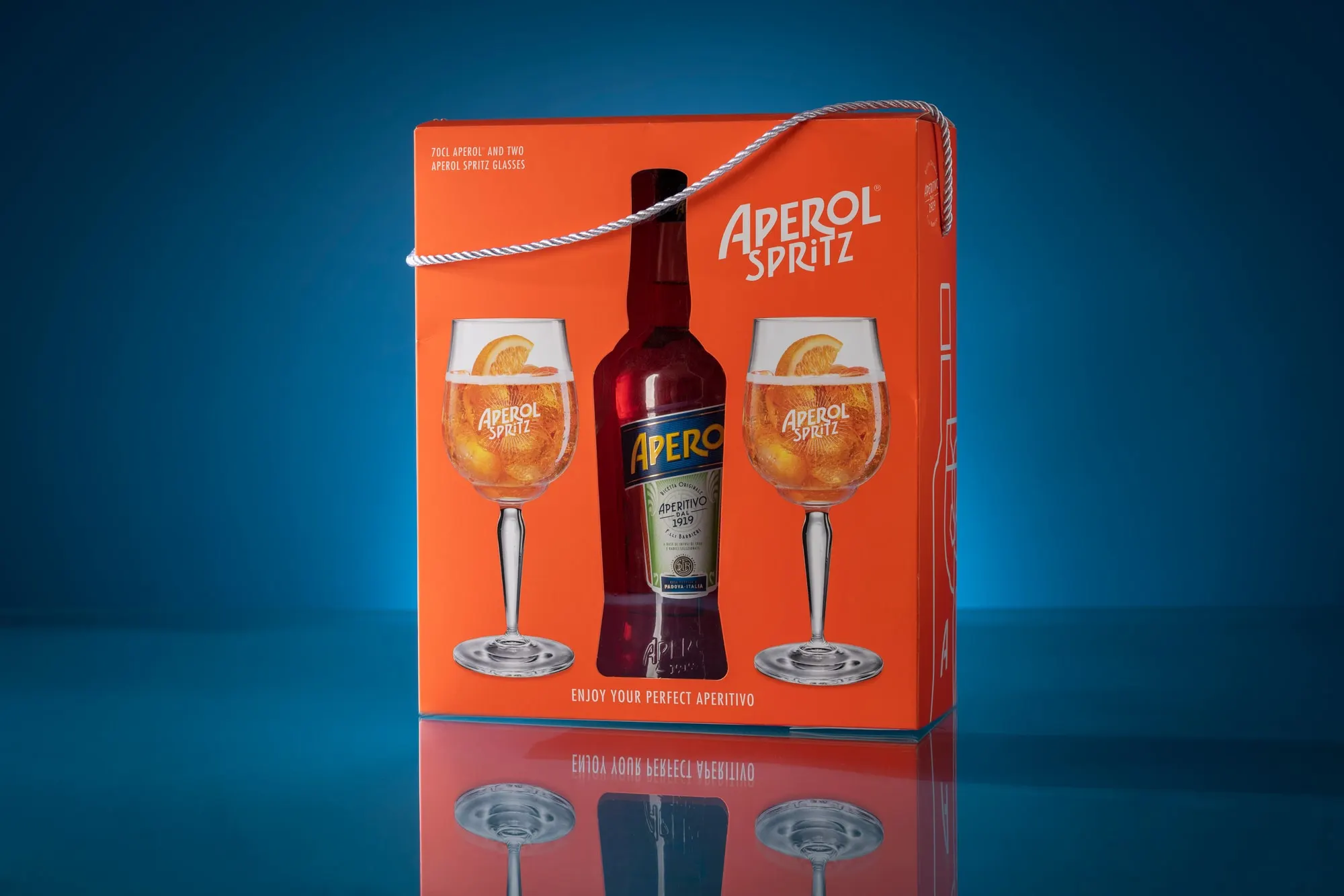 Aperol Spritz gift carton printed with the bottle and two garnished glasses, photographed against a deep blue ground