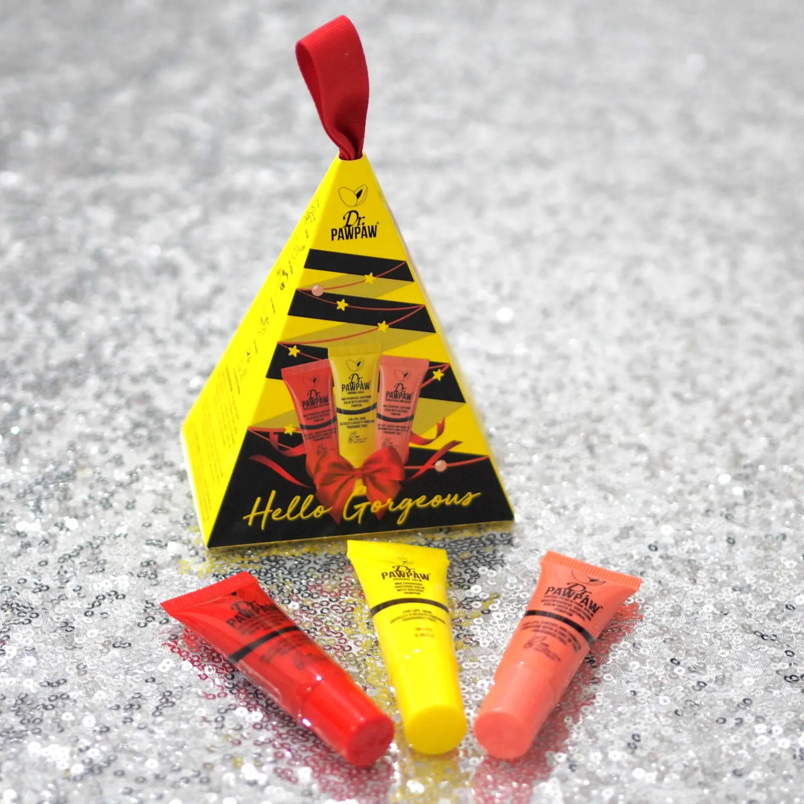 Yellow Dr PawPaw pyramid carton printed "Hello Gorgeous", with three balm tubes laid out in front of it