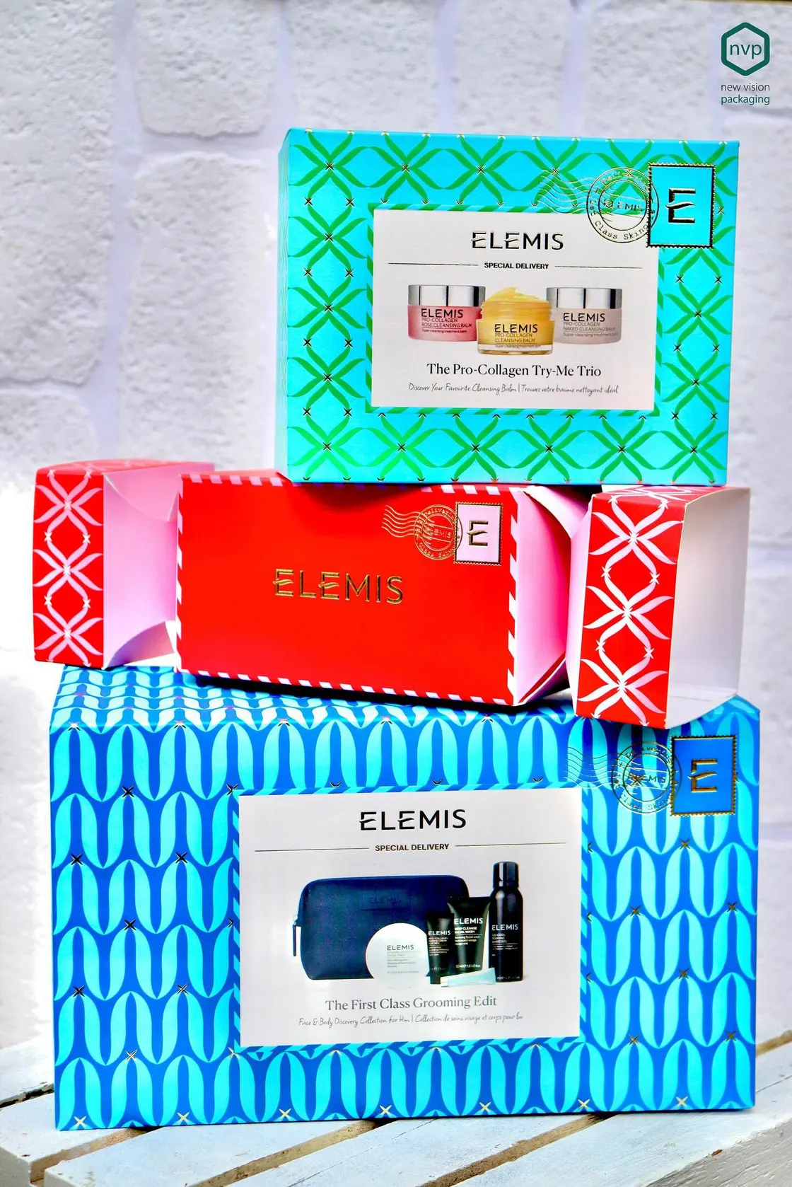 Three Elemis Special Delivery cartons in turquoise, red and blue, stacked and printed with patterned borders