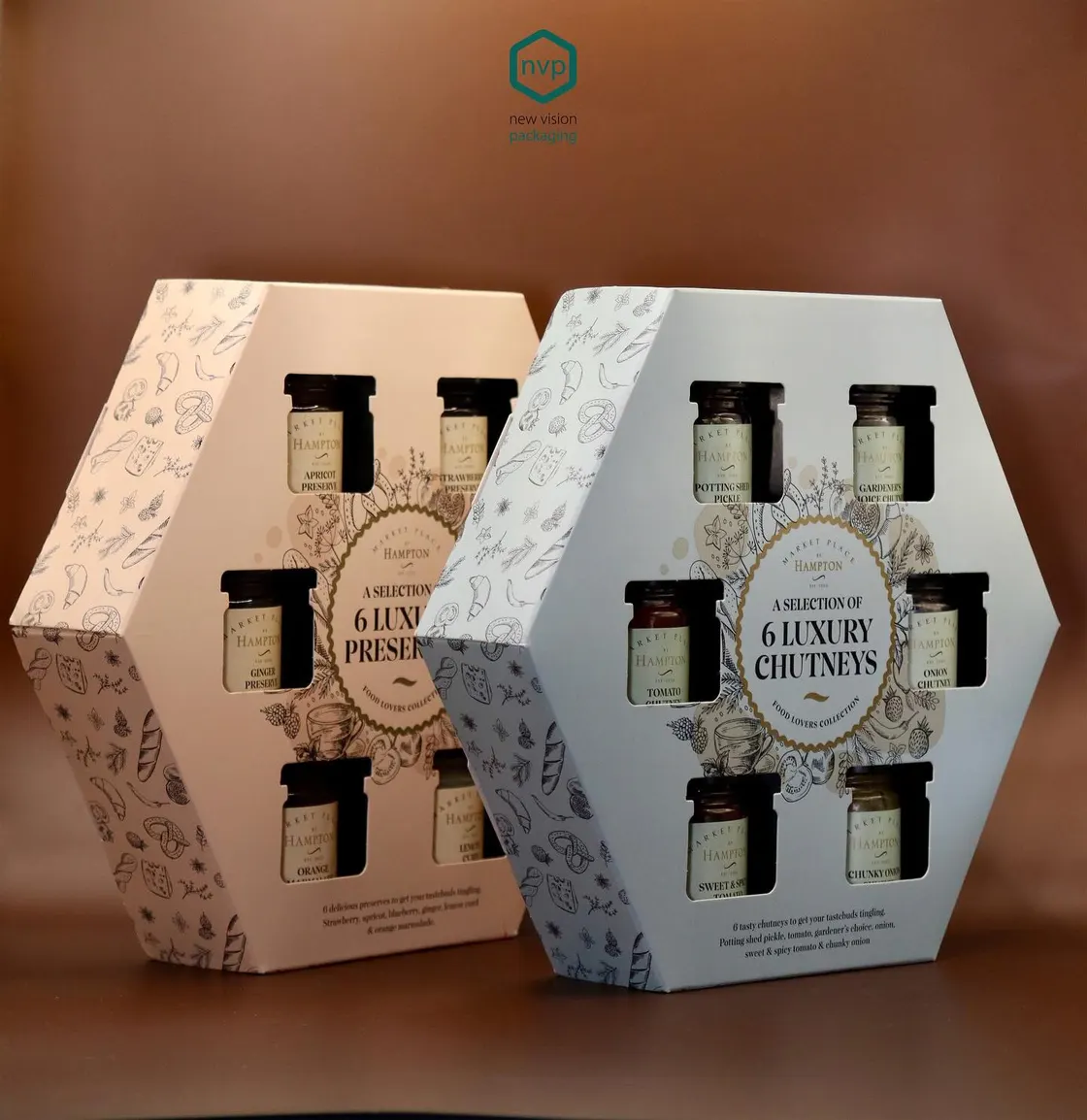 Two hexagonal Great Hampton cartons in blush and grey, each presenting six jars of preserves and chutneys behind die-cut windows