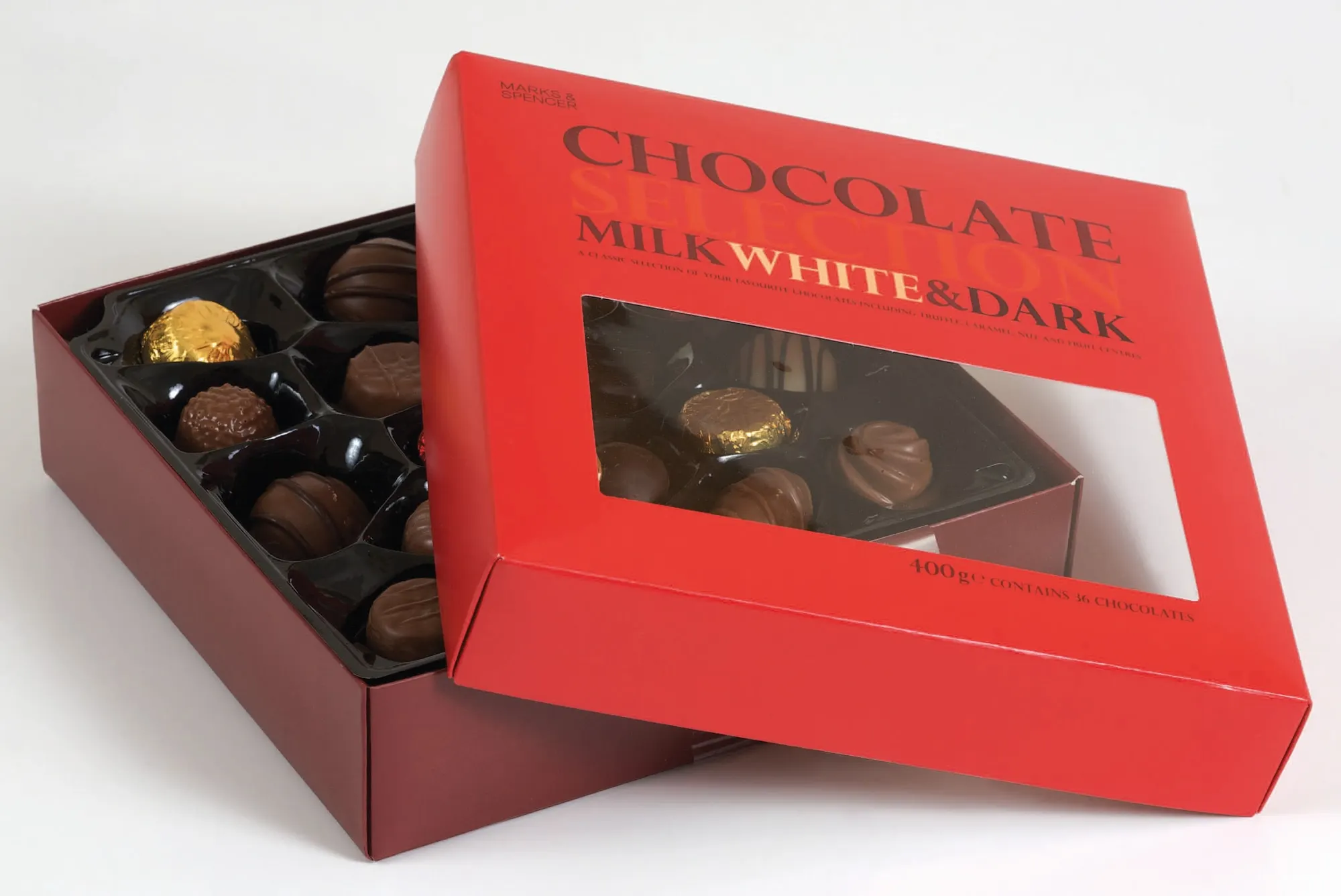 Red chocolate selection carton with a die-cut lid window, opened to show the tray of milk, white and dark chocolates