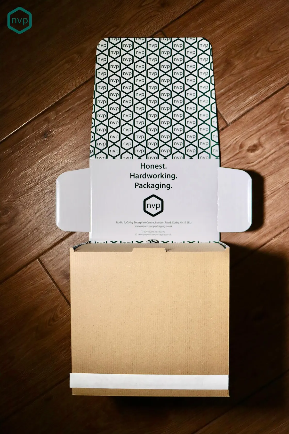 New Vision Packaging’s own corrugated mailer, printed inside with the nvp hexagon pattern and the line Honest. Hardworking. Packaging.