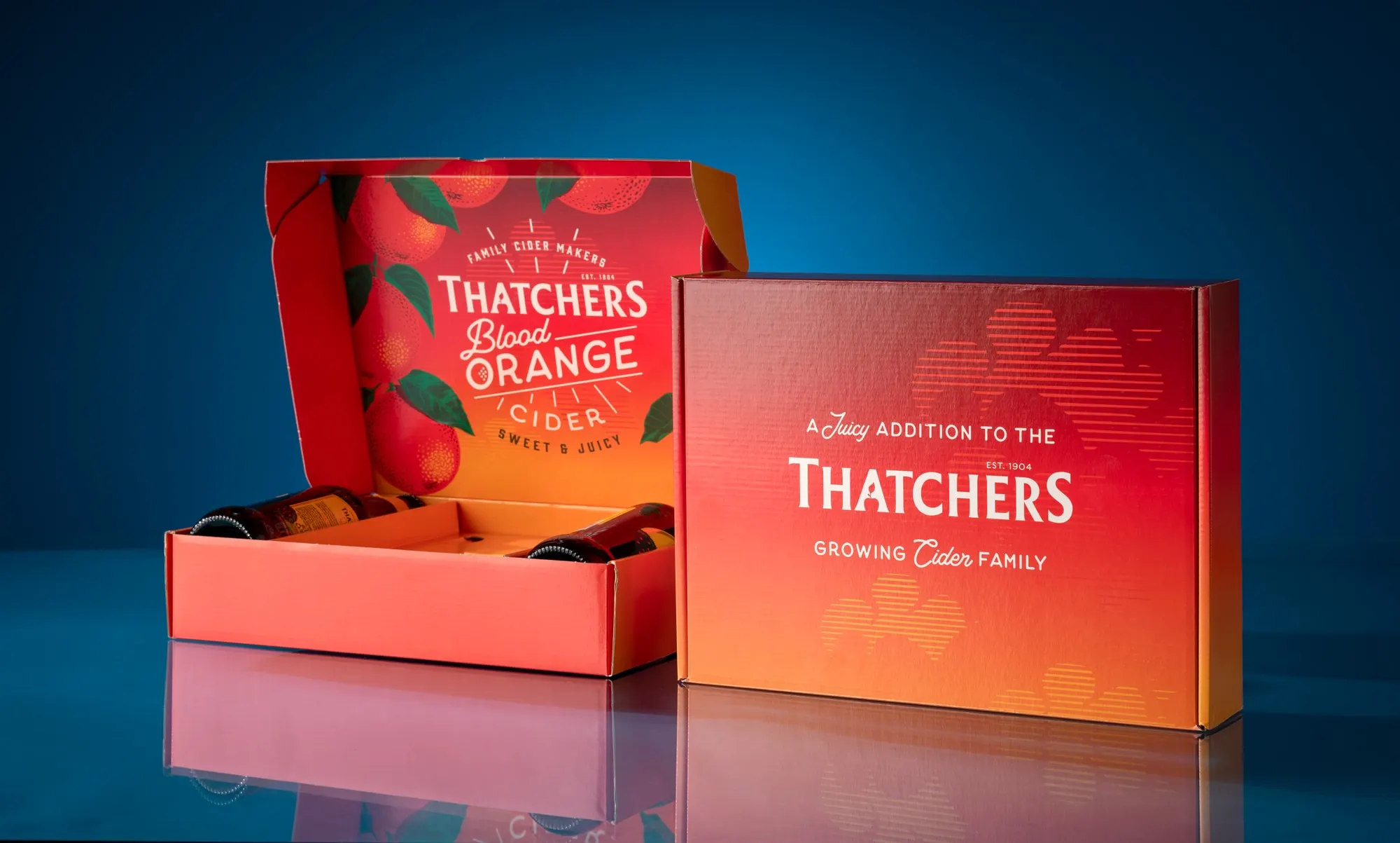 Thatchers Blood Orange corrugated gift box shown open and closed against a deep blue ground