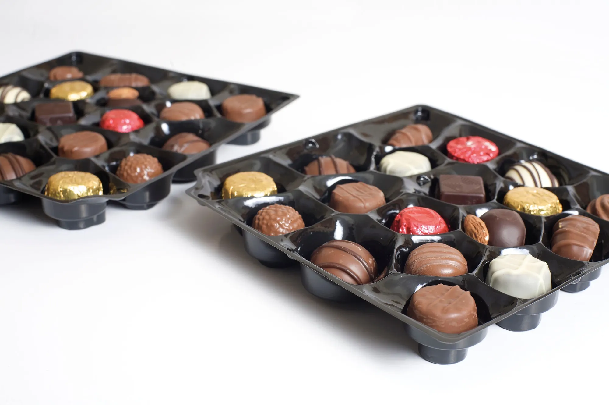 Two vacuum formed chocolate trays angled together to show the moulded cavity detail